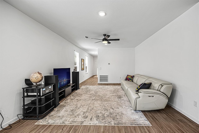 living area featuring visible vents, baseboards, a ceiling fan, and wood finished floors