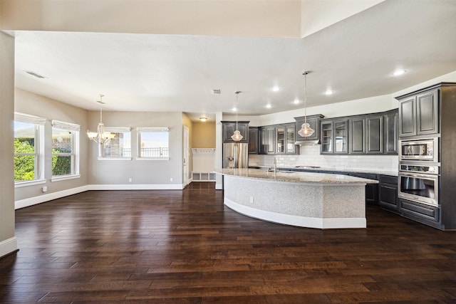 kitchen featuring dark wood-style floors, decorative backsplash, appliances with stainless steel finishes, and a sink