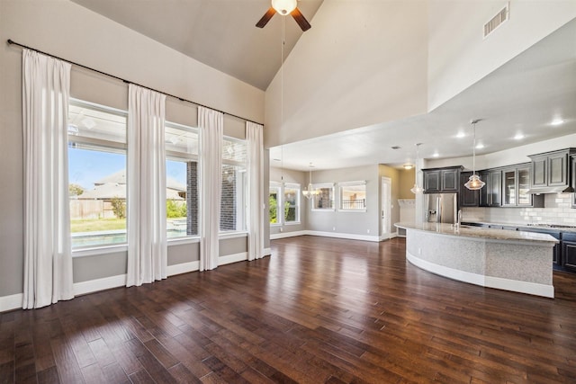 unfurnished living room featuring a sink, visible vents, baseboards, and dark wood-style floors