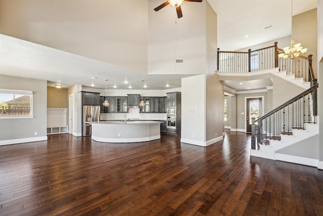 unfurnished living room with visible vents, baseboards, stairway, dark wood-style floors, and a sink