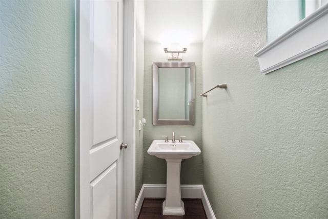 bathroom with baseboards, wood finished floors, and a textured wall