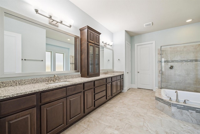 bathroom with a garden tub, tiled shower, double vanity, and a sink