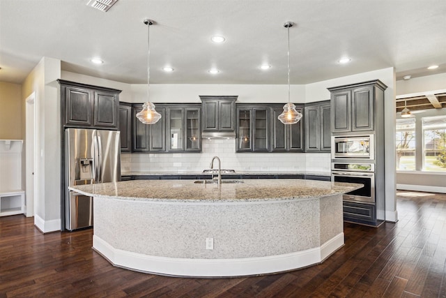 kitchen with a large island, stainless steel appliances, glass insert cabinets, and dark wood-style flooring