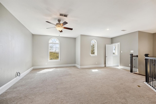 spare room with visible vents, light colored carpet, a ceiling fan, and baseboards