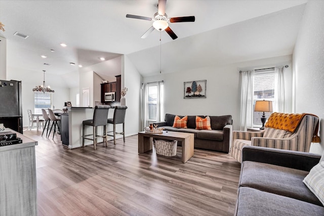 living area featuring visible vents, ceiling fan with notable chandelier, wood finished floors, recessed lighting, and vaulted ceiling