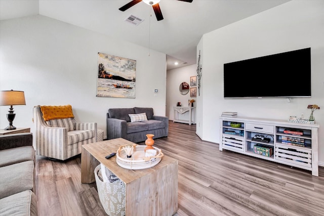 living area with visible vents, wood finished floors, ceiling fan, and vaulted ceiling