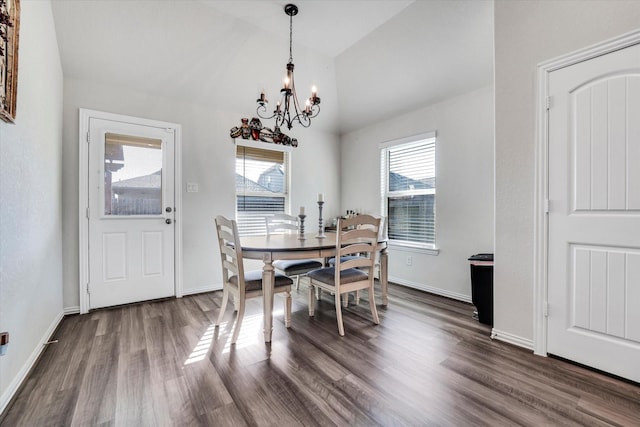 dining space featuring lofted ceiling, a notable chandelier, dark wood-style flooring, and a wealth of natural light