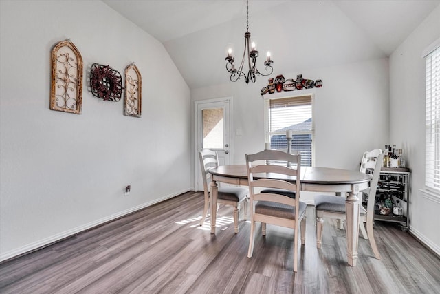 dining area with vaulted ceiling, a notable chandelier, wood finished floors, and baseboards