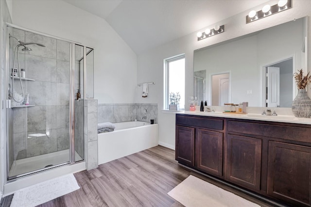 bathroom with lofted ceiling, double vanity, a stall shower, wood finished floors, and a bath