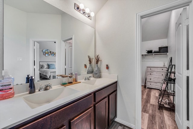 full bath with a sink, double vanity, wood finished floors, and ensuite bathroom