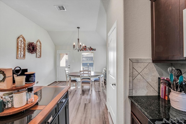 kitchen featuring light wood finished floors, visible vents, dark brown cabinetry, vaulted ceiling, and an inviting chandelier