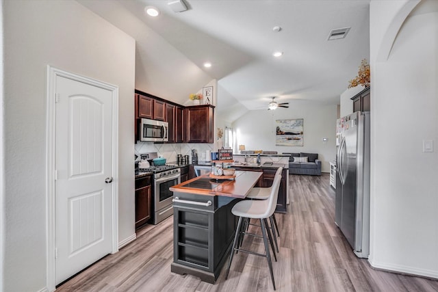 kitchen with a ceiling fan, visible vents, lofted ceiling, appliances with stainless steel finishes, and open floor plan