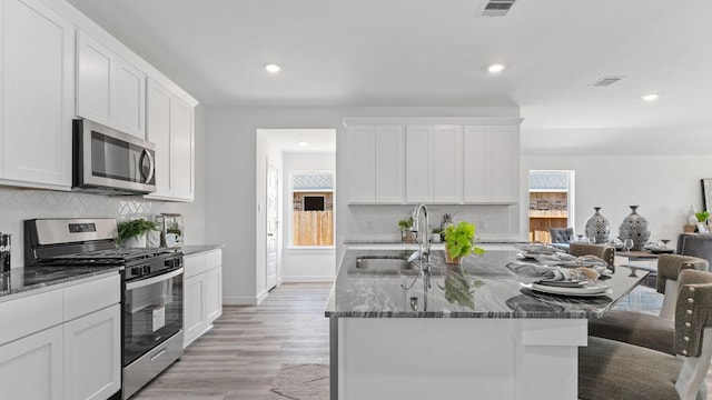 kitchen with visible vents, dark stone counters, plenty of natural light, a sink, and stainless steel appliances