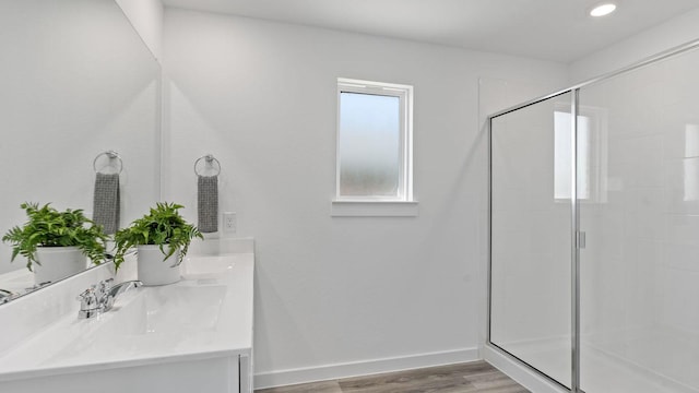 full bathroom featuring a shower stall, baseboards, double vanity, wood finished floors, and a sink