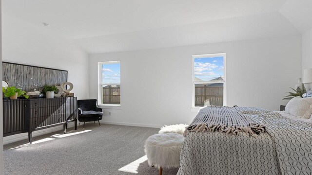 carpeted bedroom with baseboards, multiple windows, and vaulted ceiling