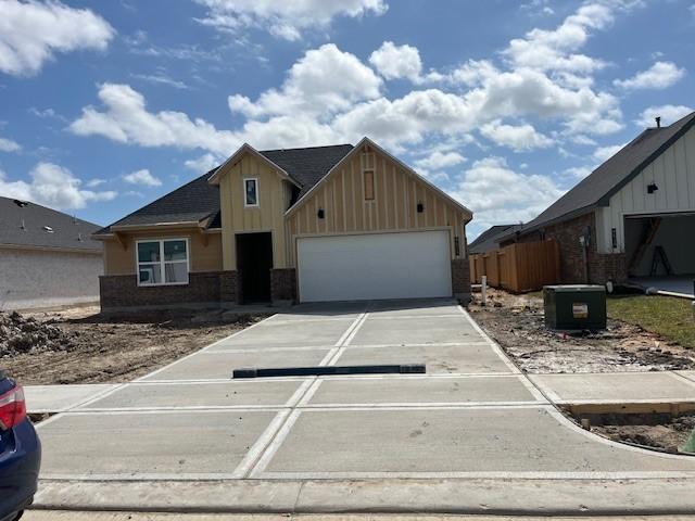 view of front of property with brick siding, board and batten siding, concrete driveway, and an attached garage