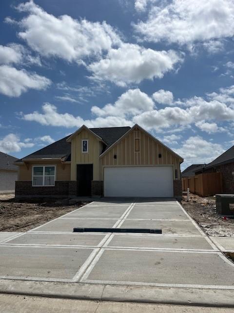 view of front of house featuring a garage, brick siding, board and batten siding, and concrete driveway