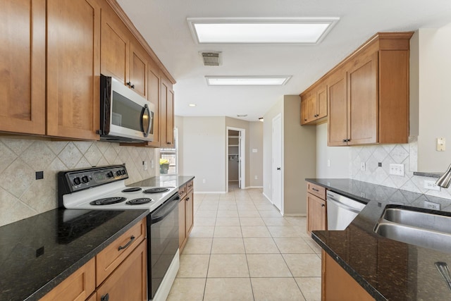 kitchen with visible vents, light tile patterned floors, brown cabinetry, stainless steel appliances, and a sink