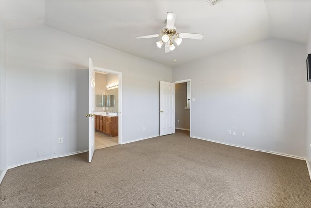 unfurnished bedroom featuring baseboards, a sink, vaulted ceiling, light carpet, and connected bathroom