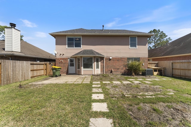 back of property with a yard, brick siding, a fenced backyard, and a patio area