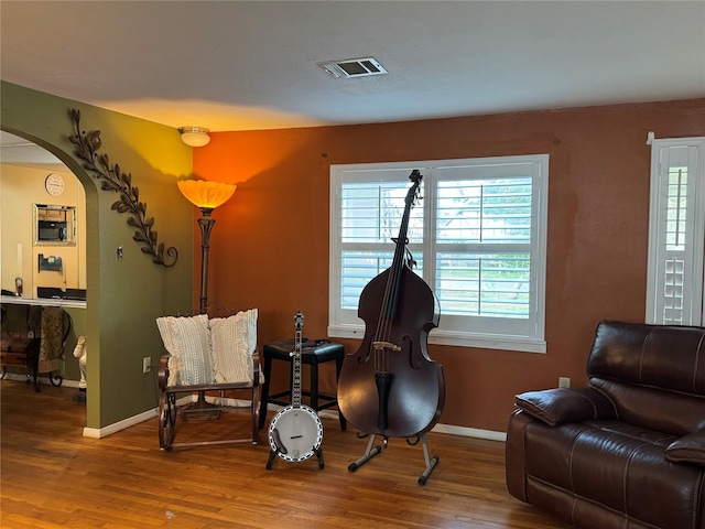 living area featuring visible vents, arched walkways, baseboards, and wood finished floors