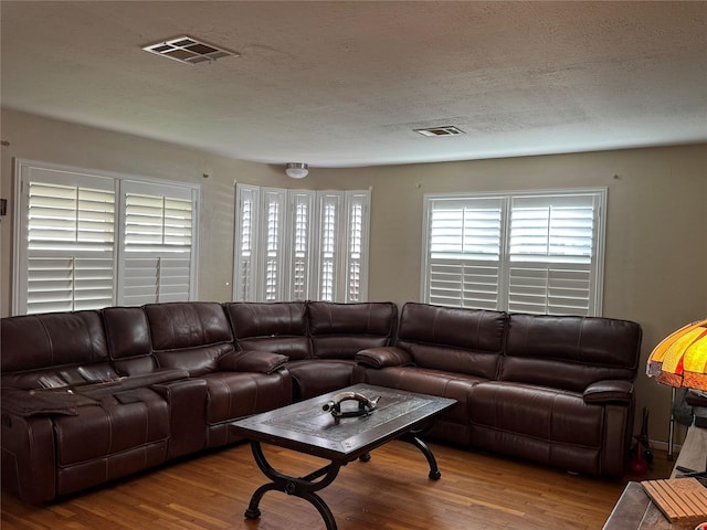 living area with visible vents, a textured ceiling, and wood finished floors