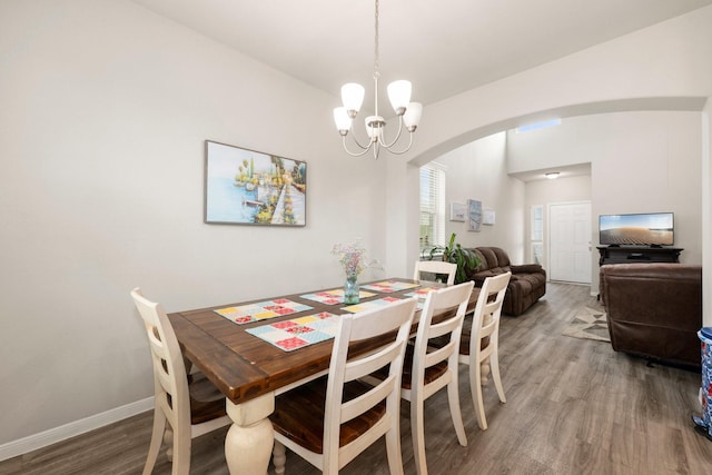 dining area featuring arched walkways, a notable chandelier, baseboards, and wood finished floors