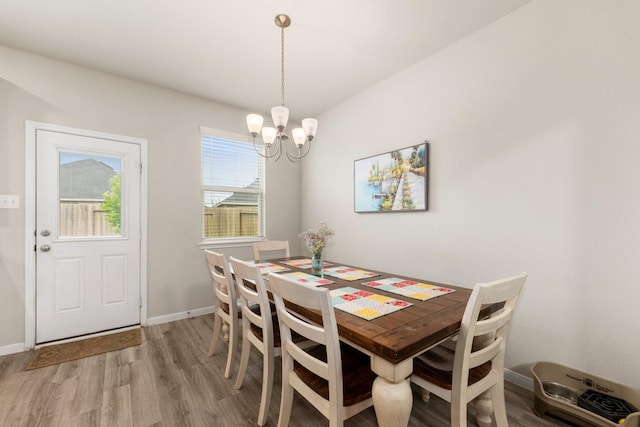 dining room with baseboards, a notable chandelier, and light wood-style flooring