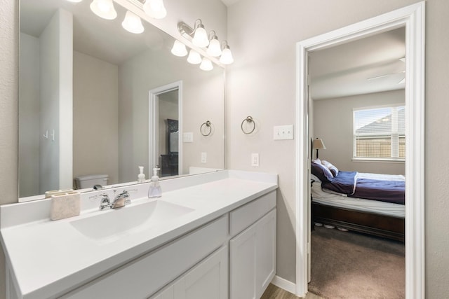 bathroom with connected bathroom, baseboards, toilet, and vanity