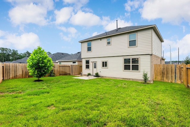 rear view of house with a lawn and a fenced backyard