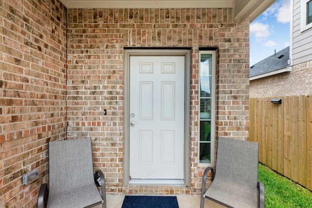 property entrance featuring brick siding and fence