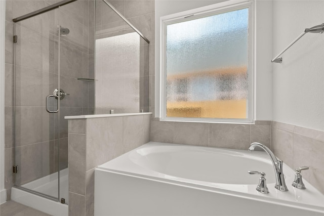 bathroom featuring a shower stall and a bath