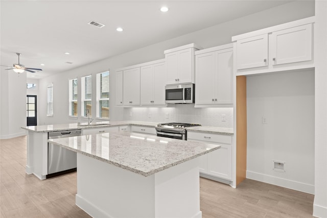 kitchen featuring visible vents, a peninsula, a sink, stainless steel appliances, and a center island