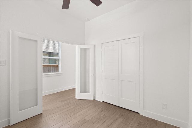 unfurnished bedroom featuring a closet, ceiling fan, baseboards, and light wood-style floors