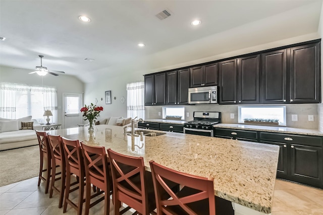 kitchen featuring visible vents, a kitchen island with sink, a sink, appliances with stainless steel finishes, and open floor plan