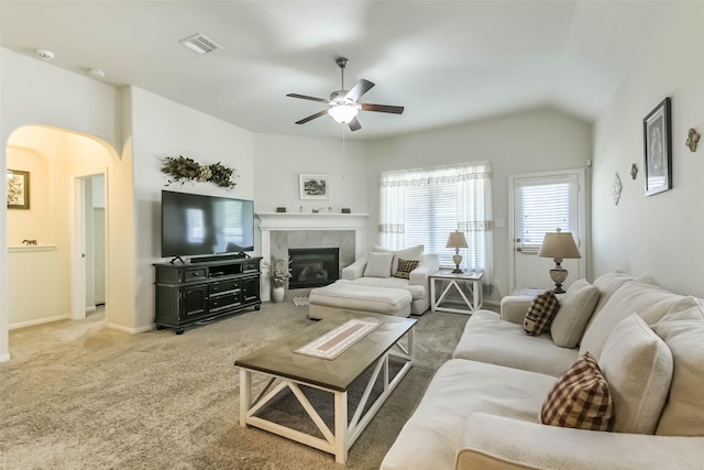 carpeted living room featuring a ceiling fan, baseboards, visible vents, a fireplace, and arched walkways