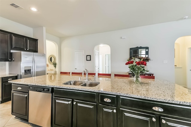 kitchen with visible vents, light tile patterned flooring, arched walkways, a sink, and appliances with stainless steel finishes