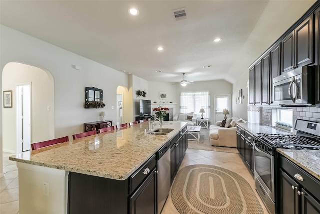 kitchen featuring visible vents, light tile patterned floors, appliances with stainless steel finishes, arched walkways, and a sink