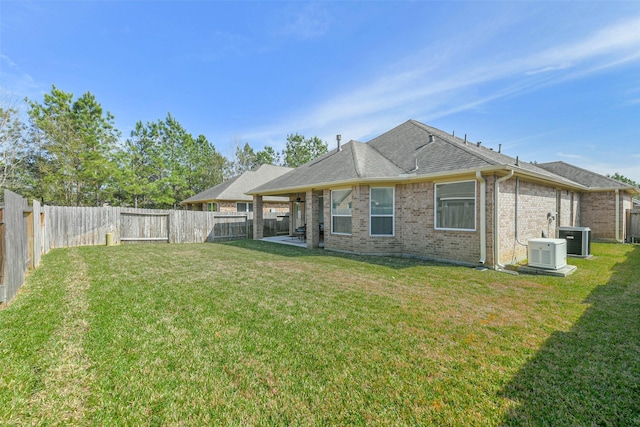 back of property with a lawn, central AC, and a fenced backyard