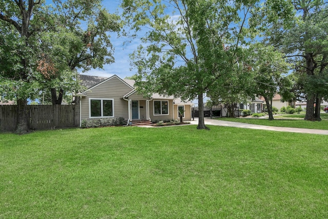 view of front of home with concrete driveway, fence, and a front lawn