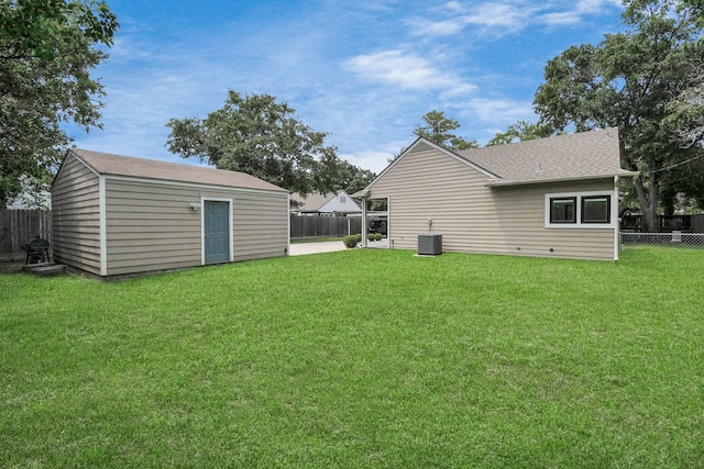 back of house featuring cooling unit, an outbuilding, a lawn, and a fenced backyard