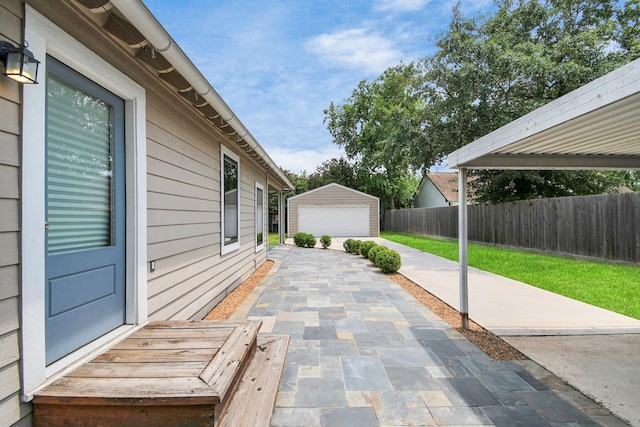 view of patio featuring a detached garage, an outdoor structure, and fence