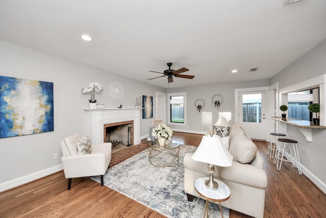 living area featuring a fireplace, recessed lighting, wood finished floors, and baseboards