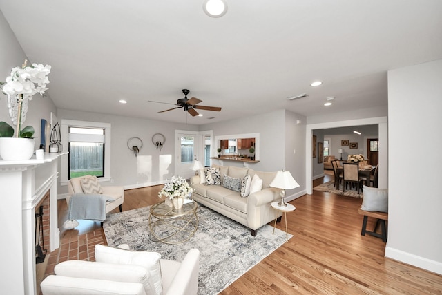 living room featuring light wood finished floors, visible vents, recessed lighting, and a fireplace