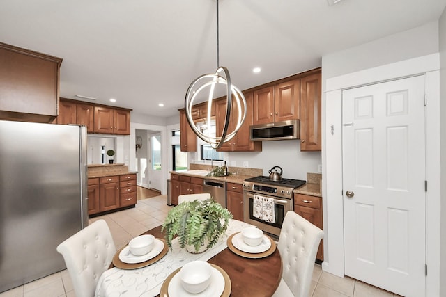 kitchen with a sink, brown cabinets, appliances with stainless steel finishes, and light tile patterned flooring