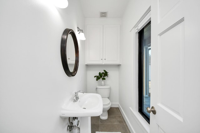 bathroom with tile patterned floors, visible vents, toilet, a sink, and baseboards