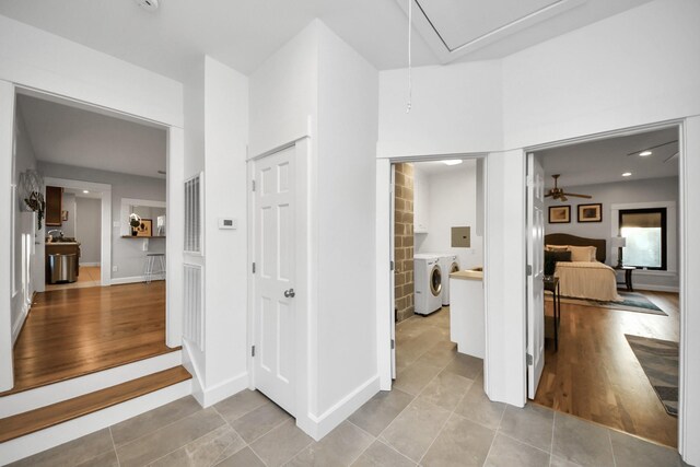 corridor featuring washer and dryer, attic access, baseboards, and light wood finished floors