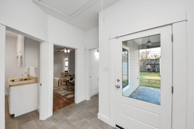 doorway to outside with light tile patterned floors, baseboards, and a sink