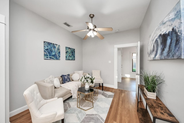 living area featuring ceiling fan, visible vents, baseboards, and wood finished floors