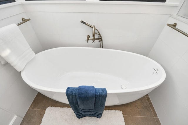 full bathroom with a freestanding tub, tile walls, and tile patterned flooring